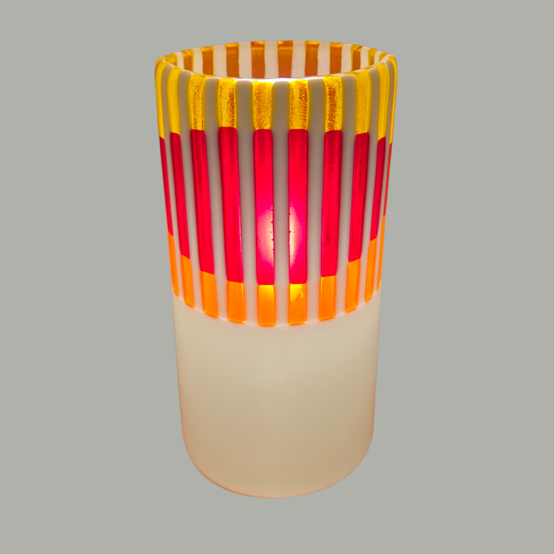 Håndlavet bordlampe i glas med stribet solnedgangsmotiv i orange og røde farver.